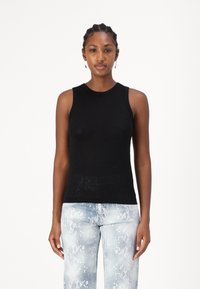 Top negro sin mangas con un diseño ajustado, textura suave, escote redondo, combinado con jeans slim de estampado de serpiente en azul claro.