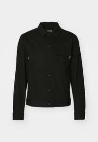 Veste noire avec fermeture à boutons, deux poches avant et une légère brillance. Fabriquée dans un tissu robuste avec un détail discret du logo sur la poitrine.