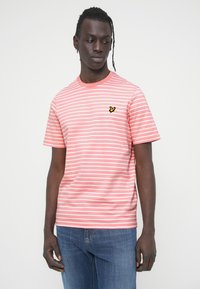 Ροζ και λευκό ριγέ μπλουζάκι με κοντά μανίκια, στρογγυλή λαιμόκοψη και μικρό μαύρο και κίτρινο λογότυπο πεταλούδας στο αριστερό στήθος.