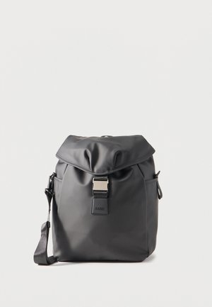 Fekete vízálló hátizsák lehajtható fedéllel, fém csattal záródik, oldalzsebekkel és állítható vállpánttal, egyszínű háttéren.