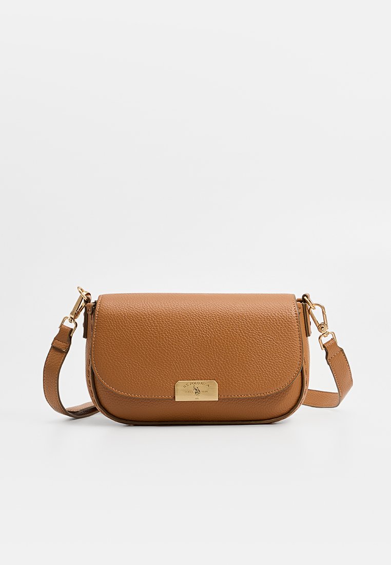 Sac en cuir tan à bandoulière avec une forme incurvée, matériel doré et une fermeture à rabat rectangulaire. Surface texturée avec une plaque de logo de la marque.
