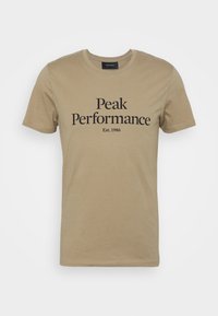 Beige bomuld t-shirt med korte ærmer og rund halsudskæring. Fronten er prydet med teksten "Peak Performance" og "Est. 1986" i sort.