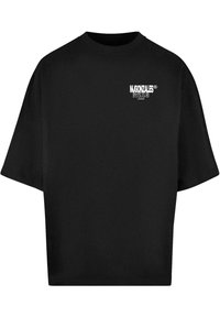 Svart oversized t-skjorte laget av bomull; har korte ermer og rund hals; inkluderer hvit trykt tekst på venstre bryst.