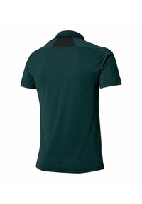 Polo de color verde oscuro con un diseño de manga corta, que presenta un panel texturizado negro en la parte posterior. Está fabricado con un material liviano y transpirable.