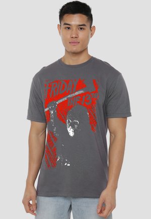 Young man wearing a gray "Friday the 13th" t-shirt featuring a masked figure holding a raised weapon in red and gray tones.