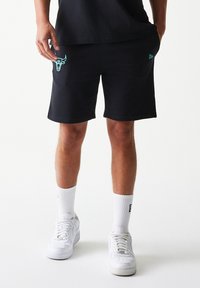 Μαύρα σορτς φούτερ με ανοιχτό μπλε λογότυπο ταύρου στο αριστερό μηρό, από απαλό ύφασμα, συνδυασμένα με λευκές κάλτσες και αθλητικά παπούτσια.