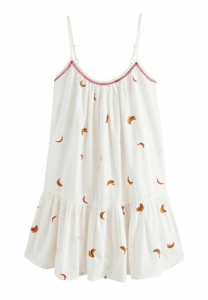 Witte mouwloze jurk met dunne bandjes, roze afwerking bij de halslijn en kleine, meerkleurige borduursels in de vorm van bananen verspreid over de stof.