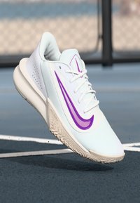 Hvide atletiske sko med en lilla swoosh, tekstureret overdel og en mønstret ydersål. Snørebånd og logo-accenter inkluderet.