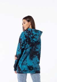 Hoodie oversize in un motivo tie-dye blu petrolio e nero, con cappuccio con lacci e polsini a costine, realizzato in morbido tessuto.