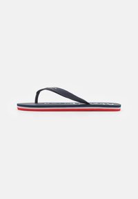 Marinblå flip-flop med ett strukturerat band, som har en vit logotyp på fotbädden och en trefärgad sula med röda och vita ränder.