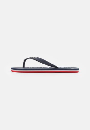 Marine flip-flops met een gestructureerde band, voorzien van een wit logo op de voetbed en een drie-kleurige zool met rode en witte strepen.