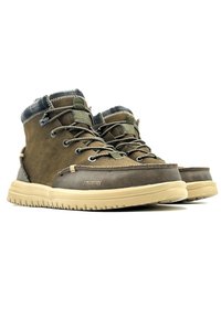 Botas de cuero y ante marrón con un cuello de tela, diseño con cordones y suela de goma. Presenta detalles de costura y un acabado texturizado.