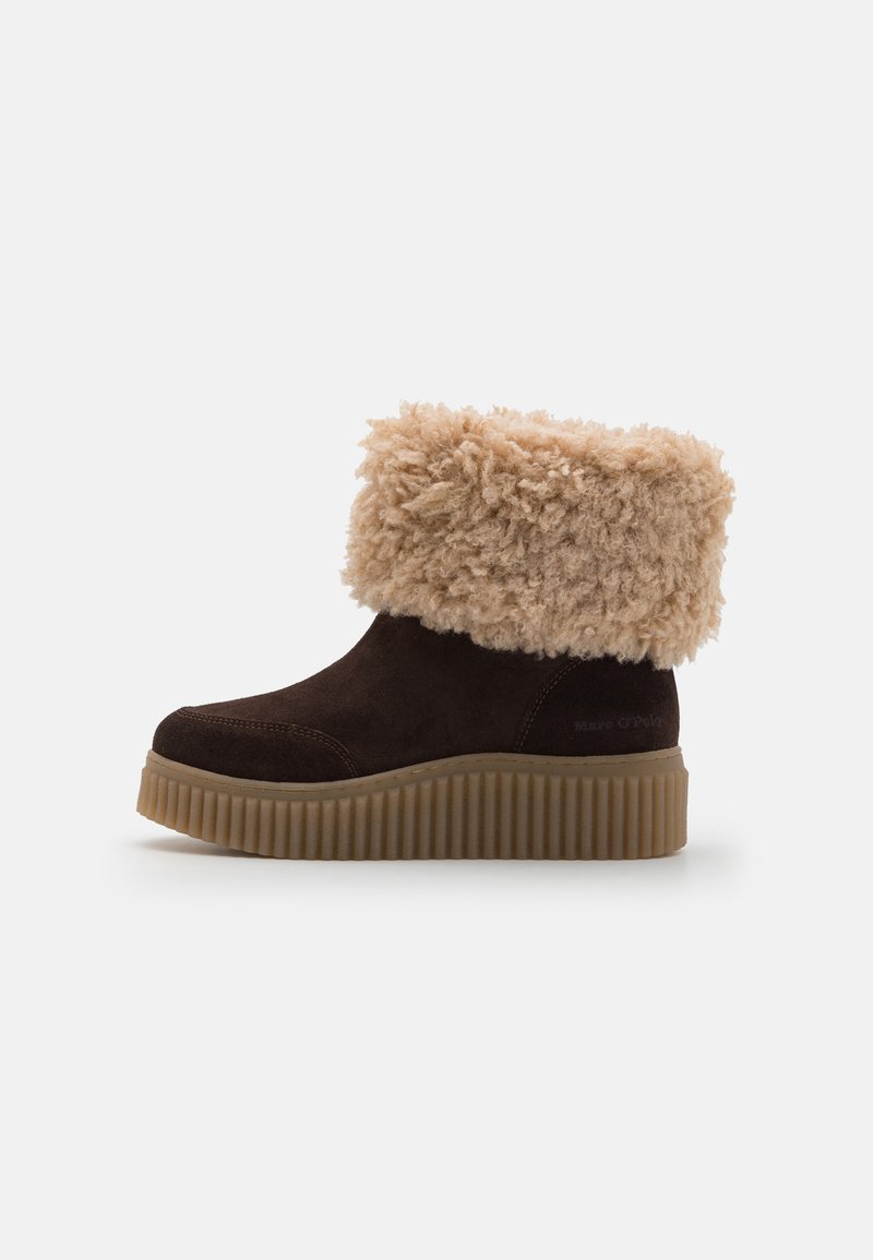 Barna velúr bokacsizmák textúrált bézs műszőrme szegéllyel és bordázott gumi talppal. Kerek orral és diszkrét márkázással rendelkezik.
