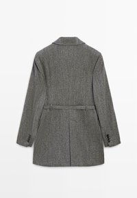 Grau strukturierte Blazerjacke mit Reverskragen, Rückengurt und Schlitzen. Verfügt über drei Knöpfe an jedem Arm und eine taillierte Silhouette.