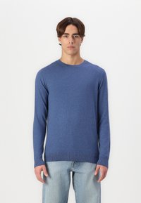 Blue long-sleeve sweater made of soft fabric. Crew neck, ribbed cuffs and hem. Paired with light blue jeans. Simple, fitted design.