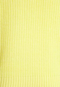 Stickad gul tröja med ett texturerat mönster och ribbade ärmslut och nederkant. Mjuk tygkvalitet med en lätt och andningsbar känsla.