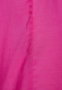Tessuto fucsia con texture liscia, caratterizzato da un sottile lucido e un design minimalista. La superficie mostra leggere pieghe e grinze.