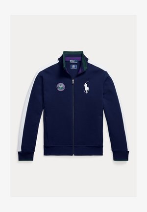 Veste zippée bleu marine avec panneaux latéraux blancs, accents verts et un logo Wimbledon. Dotée d'un col montant et d'une texture de tissu lisse.
