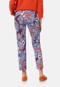Patronen broek met een bloemenontwerp in blauw, rood en wit. Gemaakt van een soepele stof met een slim fit en een verkorte lengte.