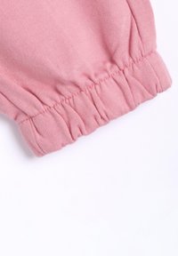 Rosa Stoff mit einem gerafften Bund; weiche Textur und leichtes Design. Der Stoff ist glatt mit einem leichten Stretch und ohne sichtbare Muster.