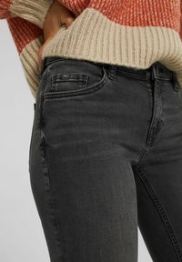 Mörkgrå jeans i denim med slim fit, med framfickor, en liten logopatch och subtila blekningar. Kombineras med en ribbad stickad tröja.