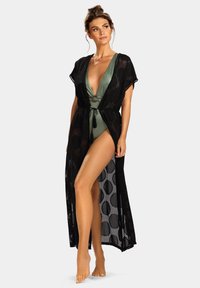 Czarny, półprzezroczysty kimono wierzchni z otwartym przodem, krótkimi rękawami i wiązaniem w talii. Pod spodem znajduje się zielony kostium kąpielowy z dekoltem w kształcie litery V i okrągłym akcentem.