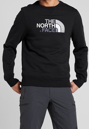 Czarny bawełniany sweatshirt z ribbanym dekoltem i dolnym wykończeniem; posiada duże szare logo z napisem "THE NORTH FACE" na wysokości klatki piersiowej.