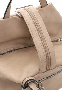 Borsa a mano in pelle beige con una superficie liscia, dotata di una cerniera argentata e un attacco per manico rettangolare. Scomparto con cerniera visibile.