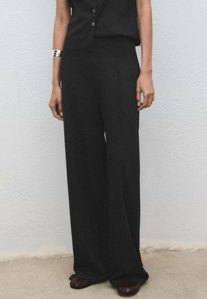Black wide-leg trousers made of soft material, featuring a high waist and a smooth texture. Paired with a simple black top and dark shoes.