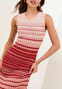 Abito in maglia senza maniche, con un motivo a zigzag ondulato nelle tonalità di rosa e rosso, con una finitura a coste strutturata.