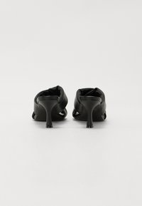 Scarpe nere con tacco alto, caratterizzate da una superficie in pelle liscia, design con apertura sul retro e un tacco a stiletto sottile e slanciato.
