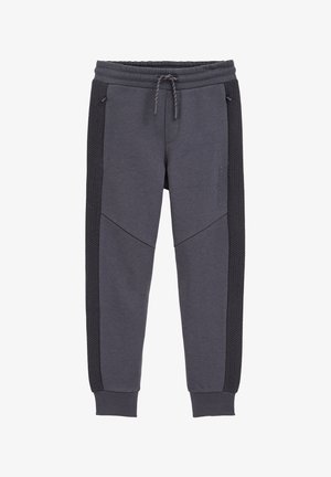 Sive trenerke slim kroja, z teksturirano stransko ploščo, elastičnim pasom in prilagodljivo vrvico.