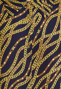 Chemise bleu marine avec un motif de chaîne et de ceinture dorés, dotée de boutons dorés sur le devant et d'un col pointu.