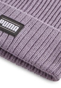 Berretto lavorato a maglia viola con texture a coste. Presenta un'etichetta rettangolare nera con lettere bianche che riportano la scritta "PUMA". Materiale morbido e caldo.
