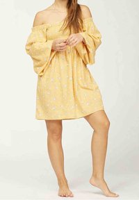 Vestido amarillo, con los hombros al aire, con mangas amplias, estampado floral y un corte suelto. Hecho de tela suave, de longitud hasta la rodilla.