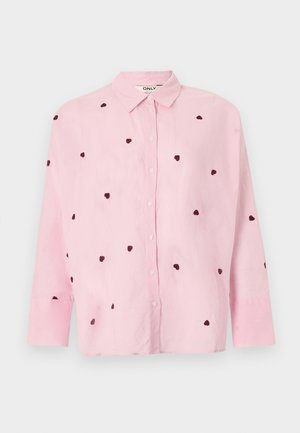 Cămașă roz deschis cu mâneci lungi și nasturi, cu modele mici în formă de inimă închise la culoare imprimate pe întreaga țesătură.