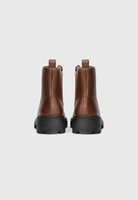 Bruna läderankelstövlar med texturerad finish, rundad tå, klumpig svart gummisula och bakre blixtlåsdetalj.