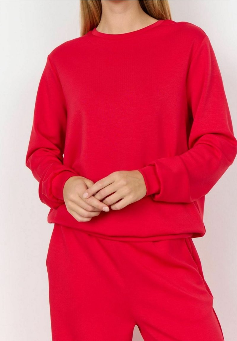 Sweat-shirt à col rond rouge en tissu doux avec manches longues, col rond et poignets côtelés, assorti à un pantalon rouge assorti.
