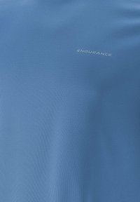 Tissu athlétique bleu avec un petit logo "ENDURANCE" gris clair imprimé sur la zone de la poitrine.