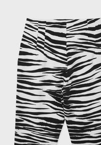 Pantaloni con un motivo a righe zebra in bianco e nero, caratterizzati da una texture liscia, una vestibilità plissettata e tagliata su misura.