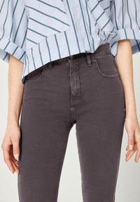 Grijze denim jeans met een soepele textuur, met een middenhoogte taille, vijf zakken en subtiele stiksels. Gecombineerd met een lichtblauw gestreept blouse.
