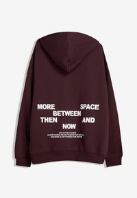 Bordeaux hoodie met een achterafdruk. Bevat witte tekst in blokken, met verschillende grootte en uitspraken, en een kangoeroezak.