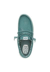Scarpa slip-on in tessuto turchese con suola bianca e lacci. L'interno presenta un motivo a zigzag. Il marchio è visibile sulla linguetta.