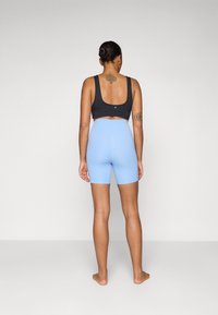 Black athletic crop top and light blue high-waisted shorts. Soft fabric, fitted design, minimal seams, and no visible logos or patterns.