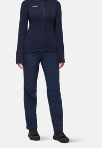 Marinblå zip-up fleecejacka med långa ärmar och två sidofickor, tillsammans med matchande marinblå byxor med snedställda fickor och en slät yta.
