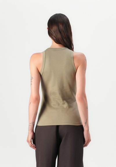 Olive green ribbed tank top with a round neckline and sleeveless design, displayed from the back, paired with dark, wide-leg trousers.
