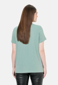 Kortærmet T-shirt med rund hals i blødt, lys grønt stof. Løse pasform med en glat tekstur, parret med tætsiddende sorte læderbukser.