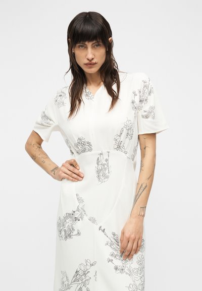 Λευκό φόρεμα με μαύρο ανθικό σχέδιο, κοντά μανίκια και V-λαιμόκοψη. Λεία υφή με σιλουέτα σε σχήμα Α και διακριτικές ραφές.