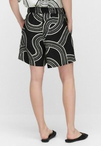 Zwarte shorts met een wit abstract golvend patroon, voorzien van een comfortabele elastische tailleband en zijzakken. Glad textuur van de stof.