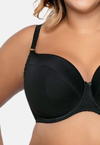 Reggiseno nero con ferretto, coppe imbottite e spalline testurizzate. Presenta un piccolo fiocco decorativo al centro e una finitura liscia.